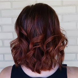 Modelo con cabello castaño oscuro y balayage caoba.